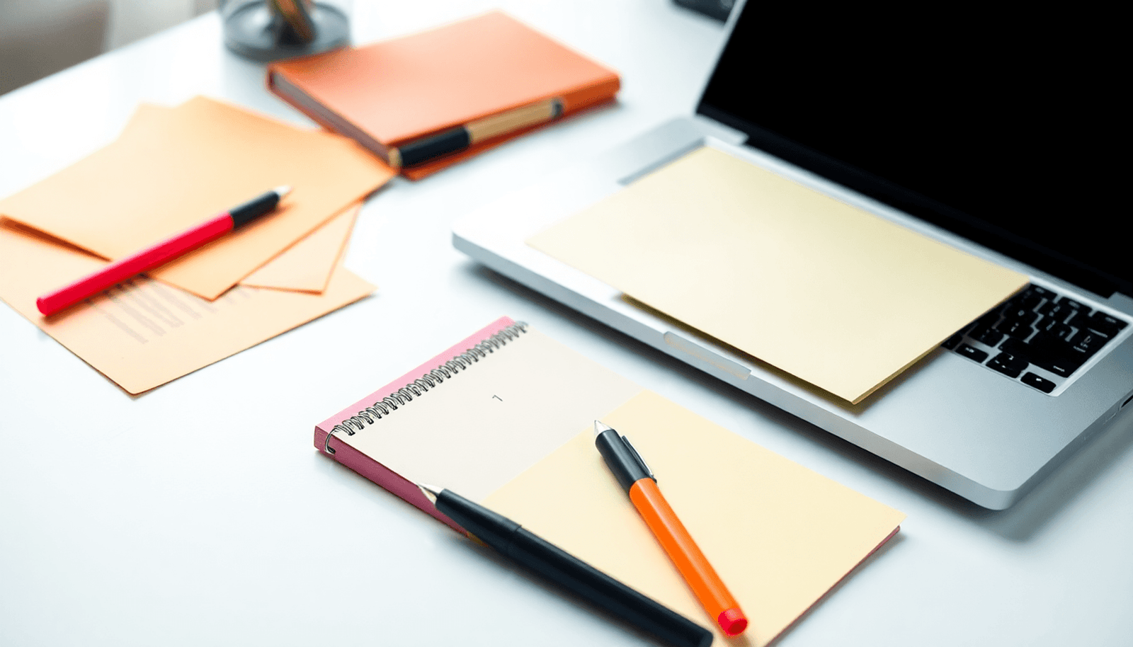 A laptop and notepad on a desk, surrounded by colorful PLR content documents, pens, and highlighters, creating a creative and minimalist workspace.